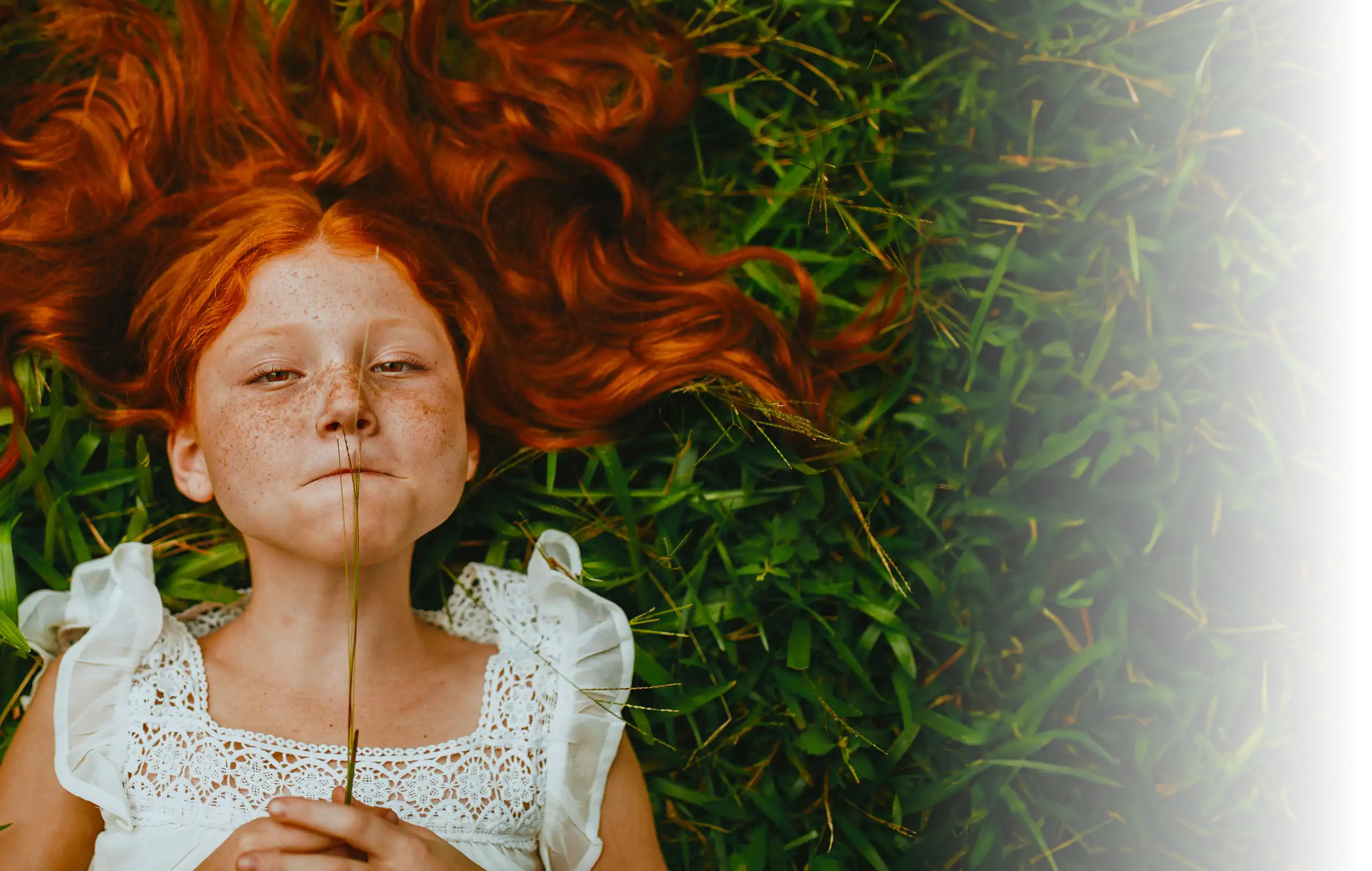 Visage d'une petite fille rousse allongée dans l'herbe